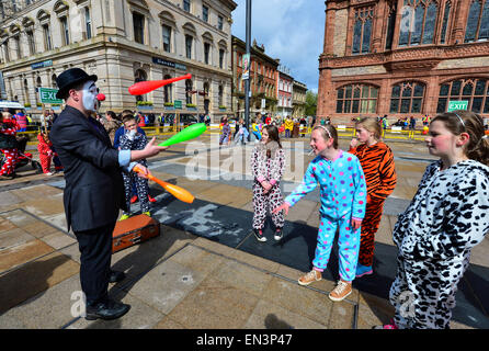 Clown mit bemaltem Gesicht, rote Nase und trägt einen Hut unterhalten Kinder gekleidet in Onesies in der Guildhall Square, Derry, Lon Stockfoto