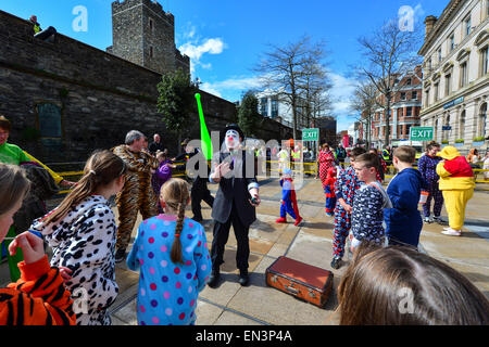 Clown mit bemaltem Gesicht, rote Nase und trägt einen Hut unterhalten Kinder gekleidet in Onesies in der Guildhall Square, Derry, Lon Stockfoto