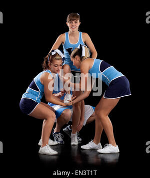 Studio shot der Cheerleader (16-17) Unterstützung Freund während der Leistung Stockfoto