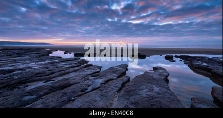 Blick auf eine erodierte Abschnitt des Strandes in Ynyslas, Wales als die Sonne beginnt am Horizont. Stockfoto