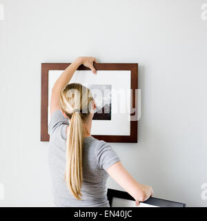 Frau, die ein Bild aufhängen Stockfoto