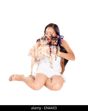 Eine schöne asiatische Frau in einem Kleid auf dem Boden sitzen und ihren zwei kleinen Hund umarmen, isoliert auf weißem Hintergrund. Stockfoto