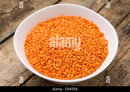 Rohe Linsen in Schüssel auf hölzernen Hintergrund. Gesunde Ernährung Stockfoto