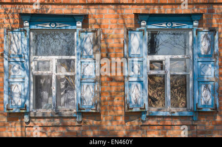 Zwei Fenster mit Fensterläden aus Holz in einem alten ukrainischen Landhaus. Stockfoto