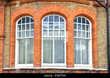 Bogenfenster in einem roten Backsteingebäude in London, Großbritannien Stockfoto