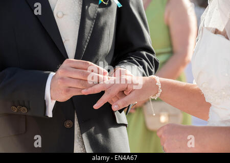 Bräutigam putting Ehering am Finger Bräute bei Trauung Stockfoto