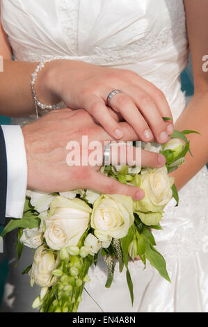 Hände einer Braut und Bräutigam bei einer Hochzeitszeremonie mit einem Blumenstrauß und Ringe Stockfoto