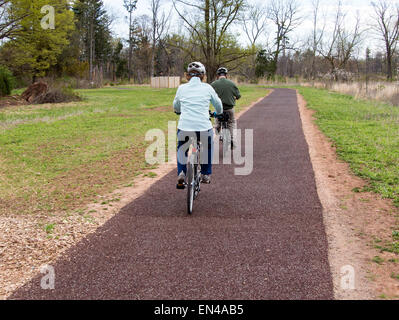 Paar senior Mann und Frau auf Fahrrädern auf einem gepflasterten Weg in den Park. Stockfoto