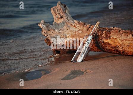 Neues Jahr 2016 eine Flaschenpost auf ein Stück Treibholz am Strand. Stockfoto