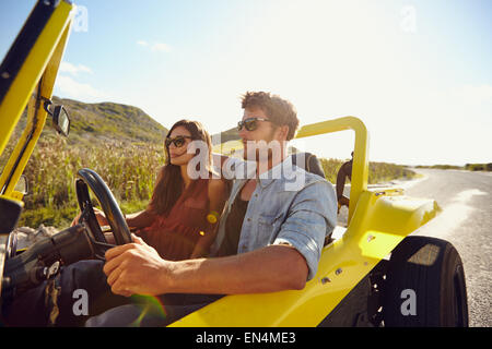 Schöne junge Paar in ihrem Auto sitzen und genießen Sie die Fahrt. Mann ein Auto auf einer Landstraße zu fahren. Paar im Urlaub. Stockfoto