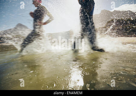 Bild von Spritzwasser während Triathleten im See laufen.  Sportler, training für Triathlon-Rennen. Stockfoto