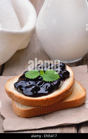 Blaubeeren Marmelade auf Toast und Krug Milch Stockfoto