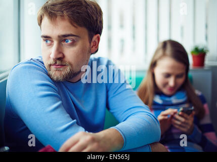 Junger Mann im blauen Pullover auf Grund seiner Freundin Stockfoto