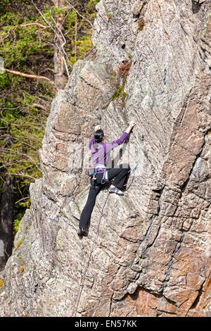 Weibliche Kletterer auf einem steilen Felsen. Stockfoto
