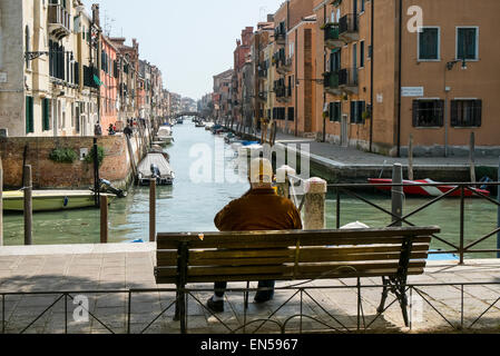 Ein Mann auf der Bank sitzen vor einem Kanal in Venedig Stockfoto