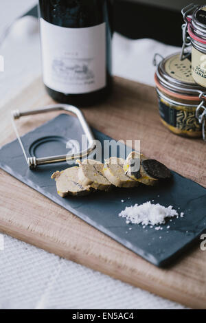 In Scheiben geschnittene Gänseleber auf eine schwarze Tafel mit schwarzem Trüffel und Meersalz Stockfoto