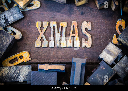 Das Wort XMAS in rostigem Metall-Lettern umgeben von Vintage aus Holz und Metall Buchdruck Art geschrieben. Stockfoto