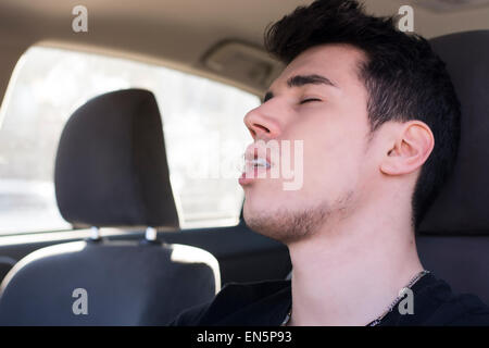 Junger Mann schlafend am Steuer seines Autos fahren Stockfoto