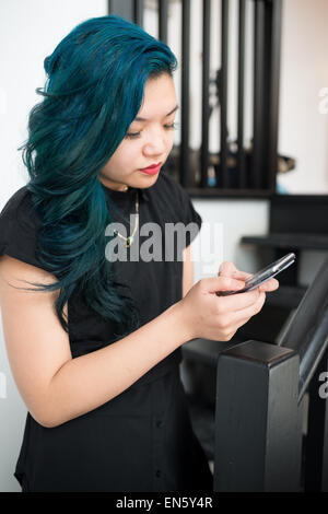 Asiatische Frau mit blauen Haaren SMS auf smartphone Stockfoto