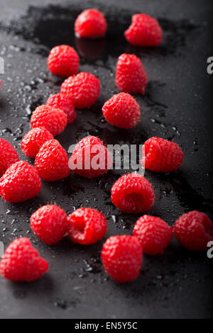 Nassen Himbeeren setzen auf schwarzem Schiefer Stockfoto