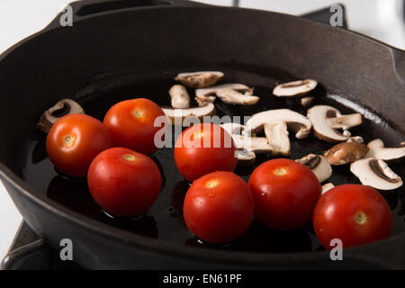 Serie: Grillen Strip Loin Steak in Gusseisen Pfanne: Zutaten, die in Scheiben geschnittenen Champignons und Tomaten zuerst vorbereitet Stockfoto