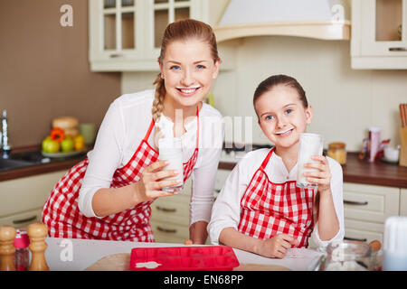 Niedliche kleine Mädchen und ihre Mutter trinken Kefir am Morgen Stockfoto