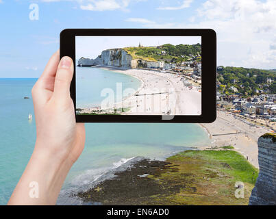 Konzept - Reisen Tourist nimmt Bild von Etretat Feriendorf am Ärmelkanal Strand der Côte d'albatre, Frankreich auf TabletPC Stockfoto