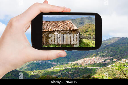 Konzept - Reisen Tourist nimmt Bild Berglandschaft mit Savoca Dorf in Sizilien im Frühjahr auf Smartphone, Italien Stockfoto