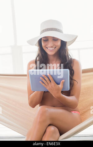 Hübsche Brünette in einer Hängematte relaxen und mit tablet-pc Stockfoto