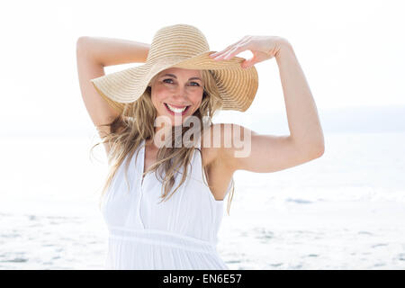 Lächelnde Blondine im weißen Kleid, Blick in die Kamera und Stroh Hut Stockfoto
