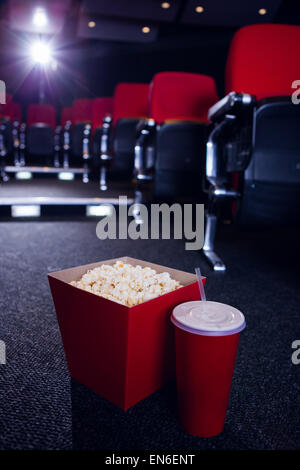 Leere Sitzreihen rot mit Popcorn und Getränken auf dem Boden Stockfoto