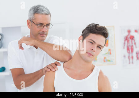 Arzt erstreckt sich einen junger Mann Hals Stockfoto