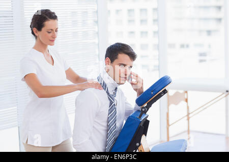 Geschäftsmann mit Rückenmassage während des Gesprächs am Telefon Stockfoto