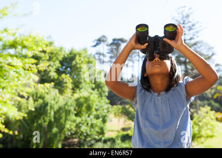 Niedliche kleine Mädchen schauen durch ein Fernglas Stockfoto