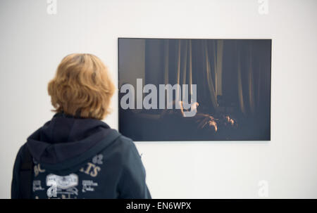 Hamburg, Deutschland. 29. April 2015. Eine Frau schaut das Siegerfoto der männliche Homosexuelle Paare in St. Petersburg, Russland, während die Ausstellung World Press Photo 2015 in Hamburg, Deutschland, 29. April 2015. Die Ausstellung läuft bis zum 31. Mai 2015 und umfasst die Gewinnerfotos des World Press Photo-Wettbewerbs. Foto: DANIEL REINHARDT/Dpa/Alamy Live News Stockfoto