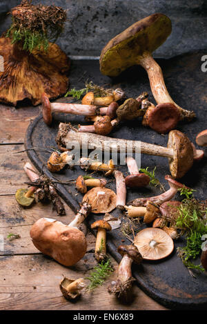 Mischung aus Wald Pilze auf schwarze Schneidebrett über alten Holztisch. Serien ansehen Stockfoto
