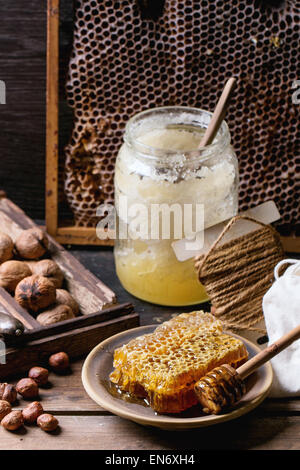 Frischen Waben mit jar von alten Honig und Mischung von Nüssen über alten Holztisch. Serien ansehen Stockfoto