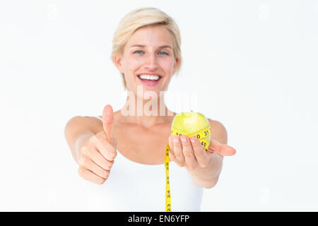 Glückliche Frau hält einen Apfel mit Daumen Stockfoto