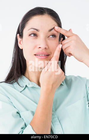 Brünette setzen ihre Kontaktlinse Stockfoto