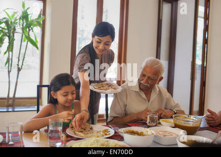 Mutter, Töchter Teller Essen aufsetzen Stockfoto