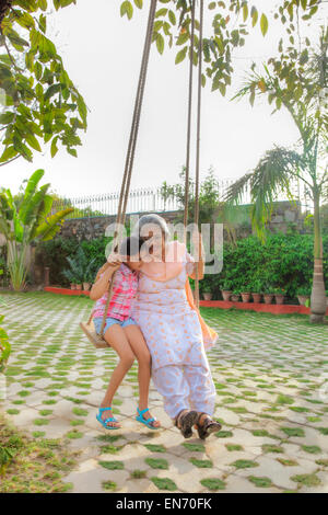 Großmutter und Enkeltochter sitzen auf einer Schaukel Stockfoto