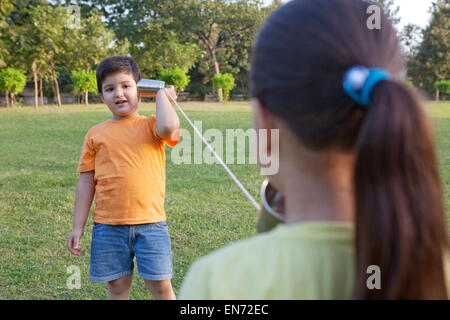 Bruder und Schwester sprechen durch Blechdosen Stockfoto