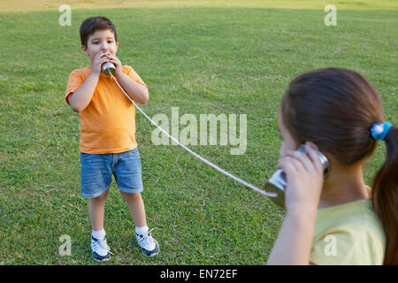 Bruder und Schwester sprechen durch Blechdosen Stockfoto