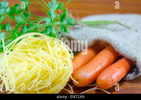 Hausgemachte Nudeln, Karotten und Petersilie auf einem Tisch Stockfoto