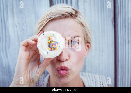 Hübsche blonde Frau mit Cupcake Grimassieren Stockfoto