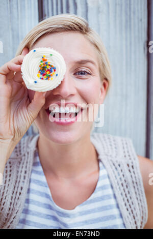 Hübsche blonde Frau mit Cupcake Grimassieren Stockfoto