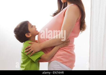 Junge Ruhe Kinn auf Bauch der schwangeren Mutter Stockfoto