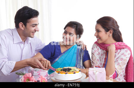 Frau schneiden Geburtstagskuchen mit einem Messer Stockfoto