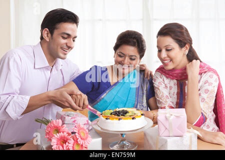 Frau schneiden Geburtstagskuchen mit einem Messer Stockfoto
