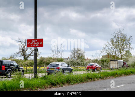 Eine "Neue Straße Layout voraus" Zeichen an einer Hauptstraße in der Nähe eine verkehrsreiche Kreuzung am Stadtrand von Cirencester mit fließenden Verkehr außerhalb Stockfoto